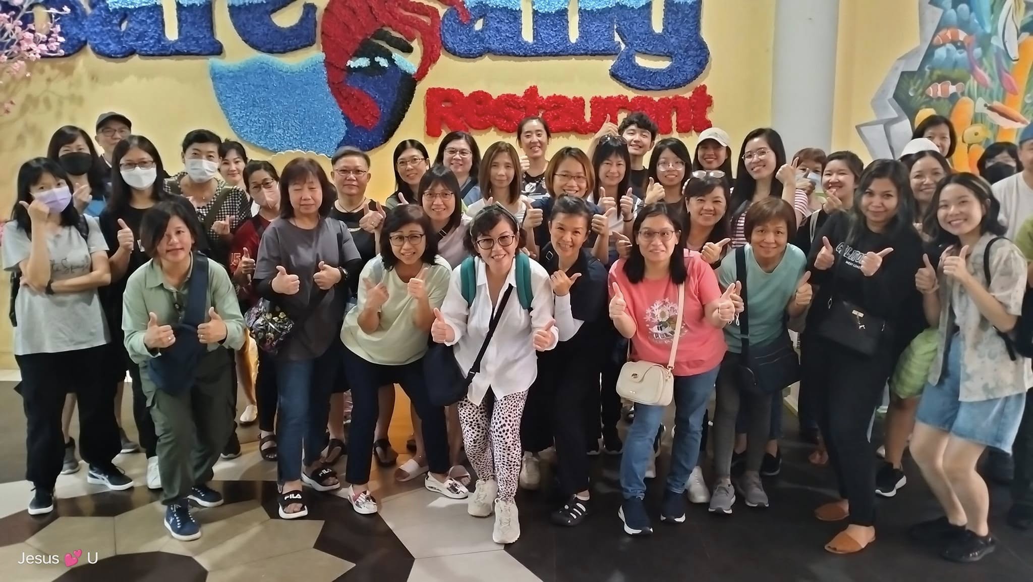 A Happy Joy Travel tour group smiling and giving thumbs-up while taking a group photo at an indoor attraction. Happy Joy Travel 旅游团在室内景点开心合影，大家面带笑容并竖起大拇指。